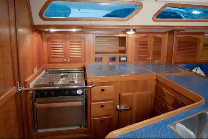 Blue Sky Yacht Photos Pics Interior of a 2000 Sabre 402 yacht kitchen with wooden cabinetry and stainless steel stove.