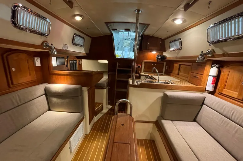 Felicity Yacht Photos Pics Interior of a 1997 Pacific Seacraft 34 sailboat with cozy seating and wooden finishes.