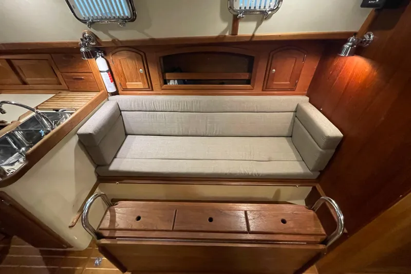 Felicity Yacht Photos Pics Interior of 1997 Pacific Seacraft 34 sailboat with cushioned seating and wooden cabinetry.
