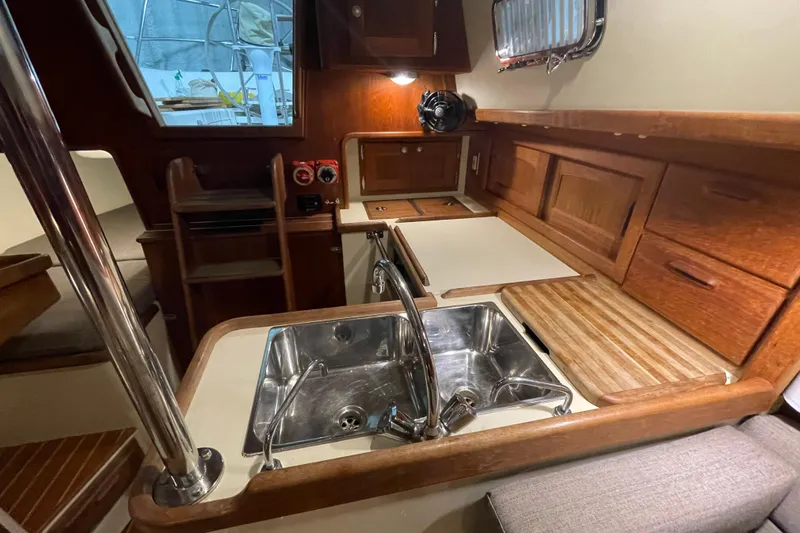 Felicity Yacht Photos Pics Interior of a 1997 Pacific Seacraft 34 sailboat, featuring a compact kitchen with wooden cabinetry.