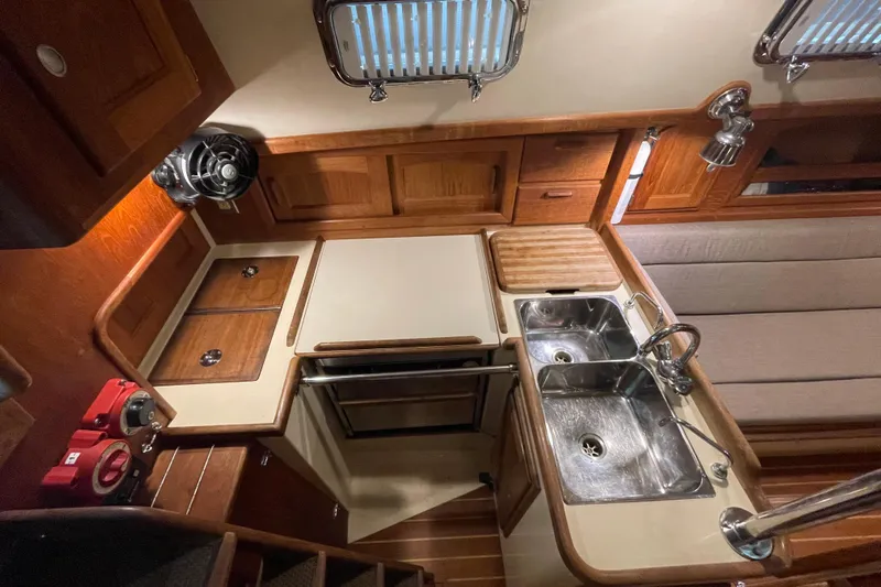 Felicity Yacht Photos Pics Interior of 1997 Pacific Seacraft 34 sailboat, featuring a compact kitchen with wooden cabinetry.