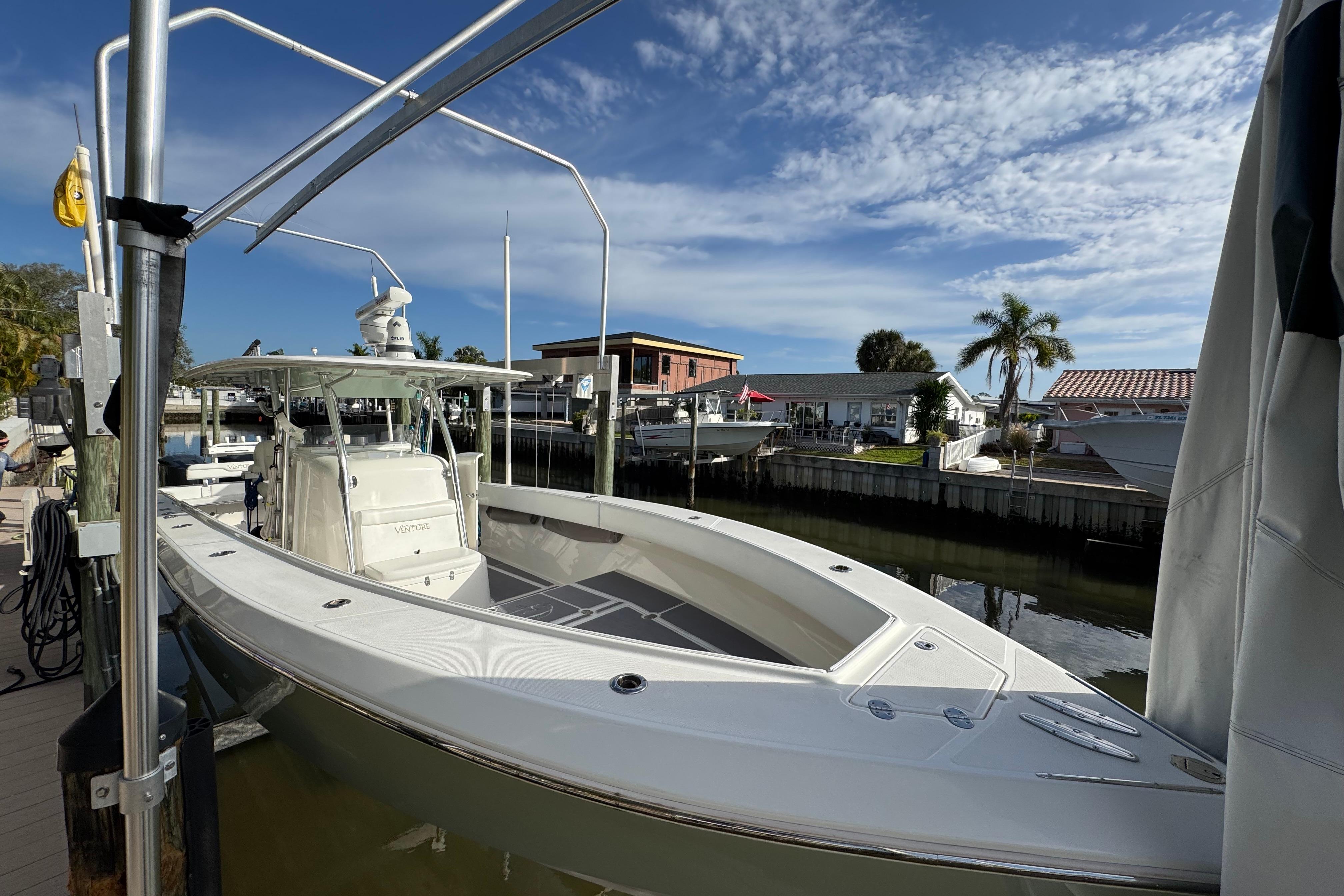 2009 Venture 39 Center Console boat docked by waterfront homes under a clear sky.