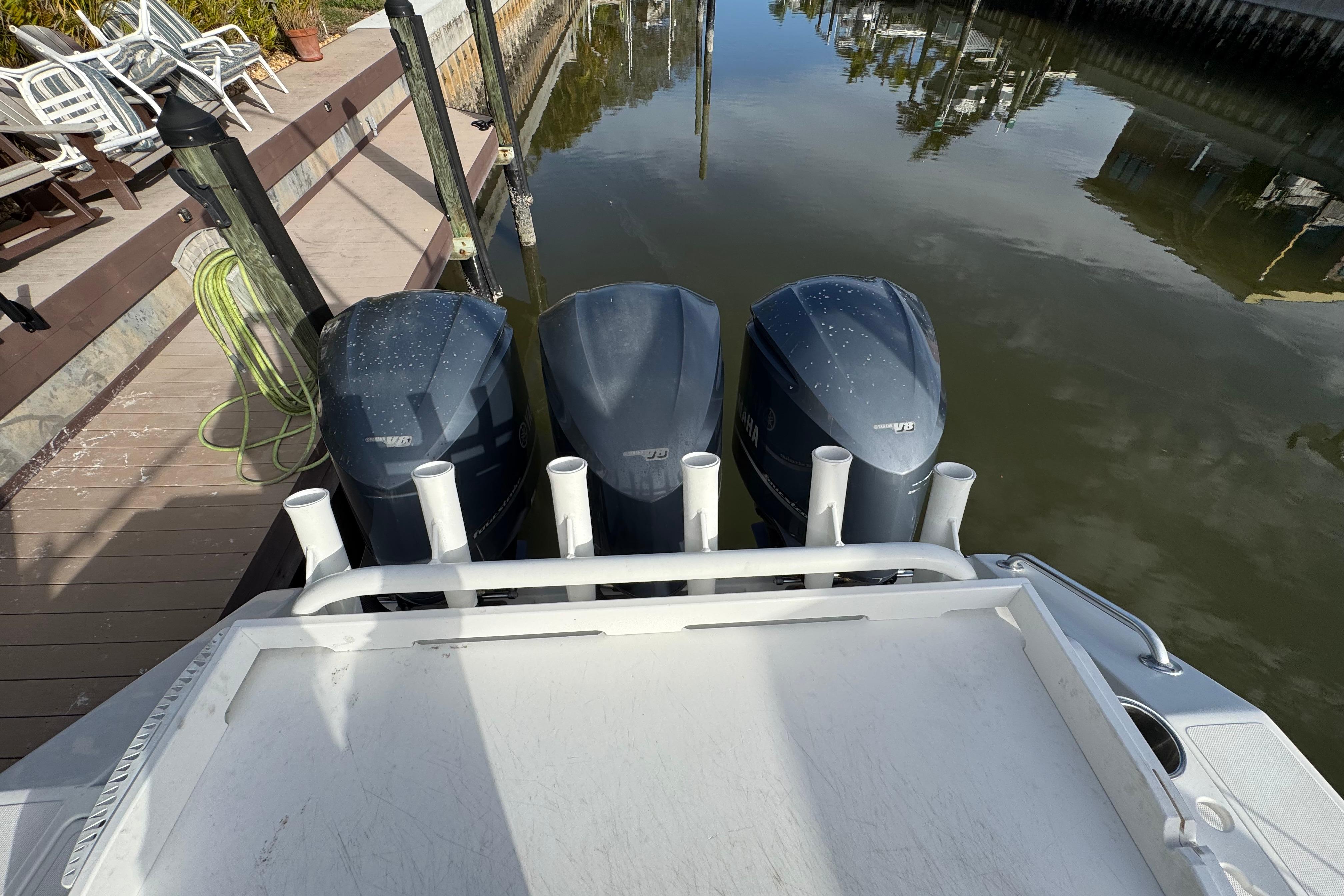 2009 Venture 39 Center Console with triple outboard engines docked by a wooden pier.