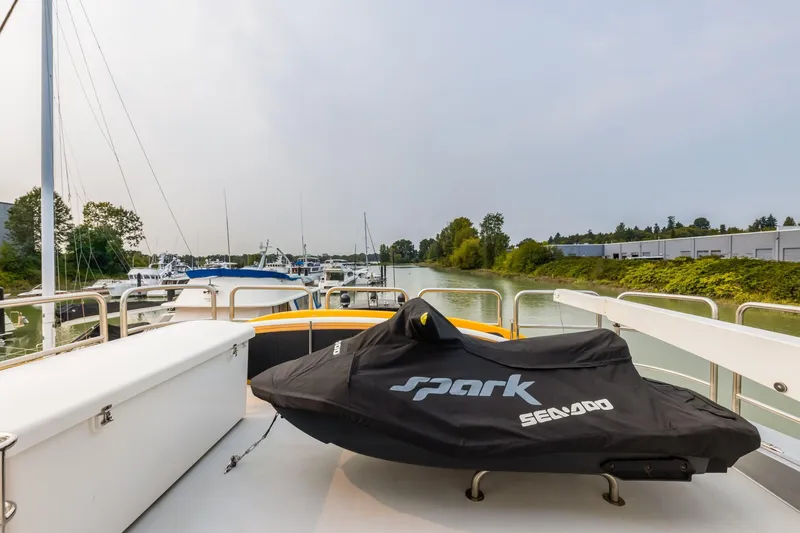  Yacht Photos Pics Primorets Custom 2010 boat with covered Sea-Doo Spark, docked in a serene marina.