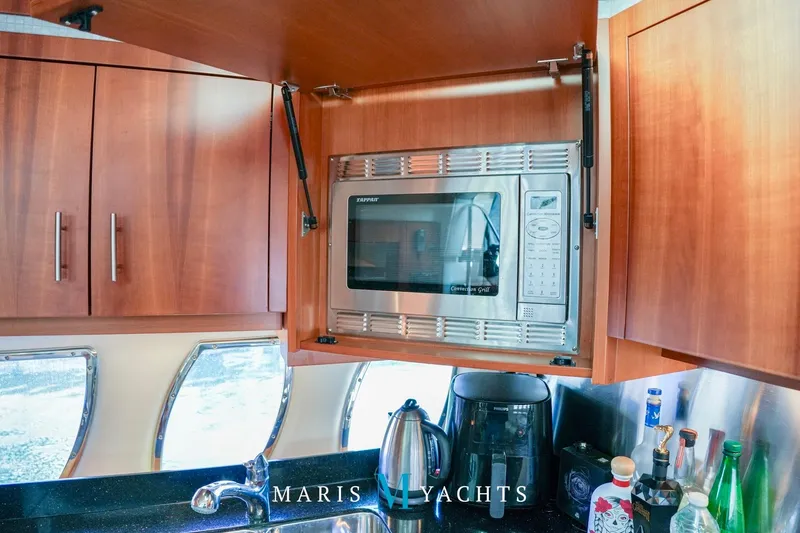  Yacht Photos Pics 2009 Regal 52 Sport Coupe yacht kitchen with microwave, kettle, and wooden cabinets.