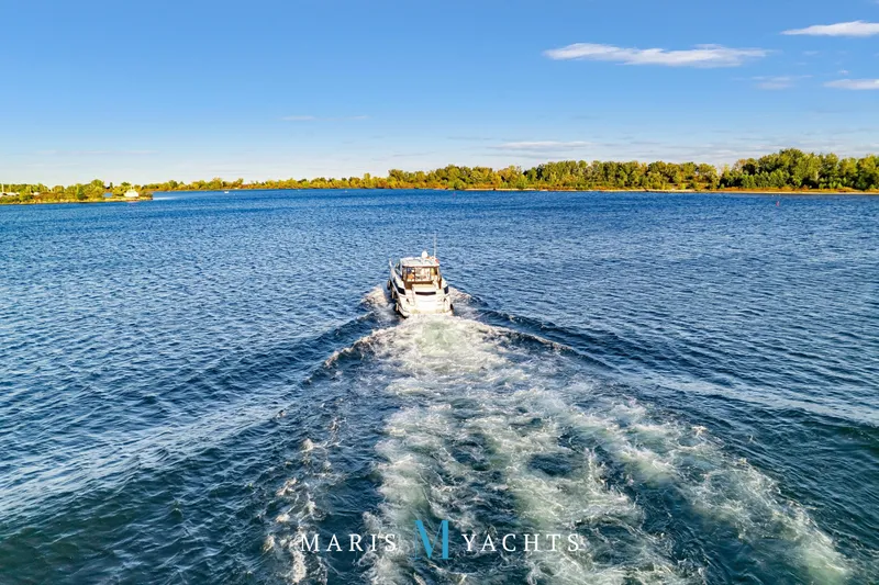  Yacht Photos Pics 2009 Regal 52 Sport Coupe cruising on a serene lake under a clear blue sky.