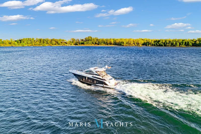  Yacht Photos Pics 2009 Regal 52 Sport Coupe yacht cruising on a sunny day, surrounded by blue water and lush greenery.
