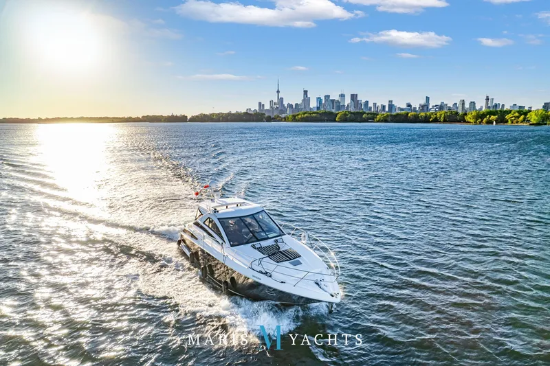 Yacht Photos Pics 2009 Regal 52 Sport Coupe yacht cruising on a sunny day with city skyline backdrop.