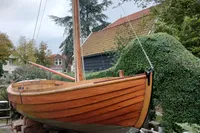 Wooden sailboat "Snipa" 2023 model, displayed outdoors on a grassy area.