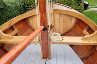 Wooden boat interior with mast and ropes, Custom Snipa model, 2023, in a garden setting.