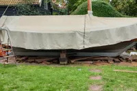 Covered Custom Snipa boat from 2023 on grass with trees and house in background.