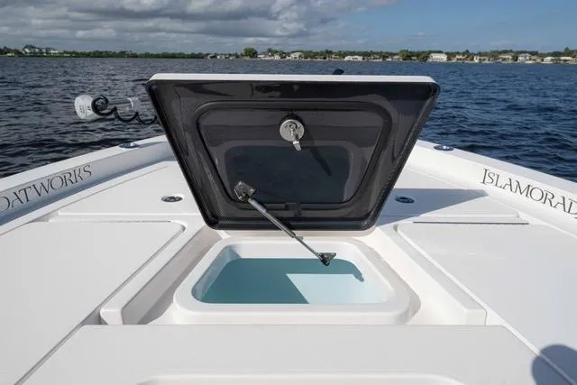  Yacht Photos Pics 2024 Islamorada Boatworks 24 with open hatch, on calm water, showcasing storage compartment.