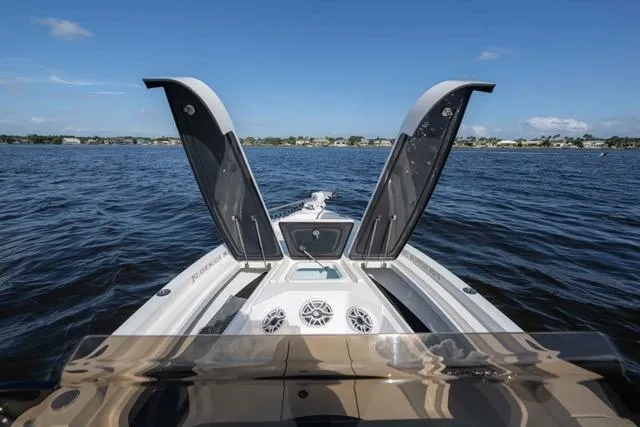  Yacht Photos Pics 2024 Islamorada Boatworks 24 on water, open storage compartments, clear sky, and distant shoreline.