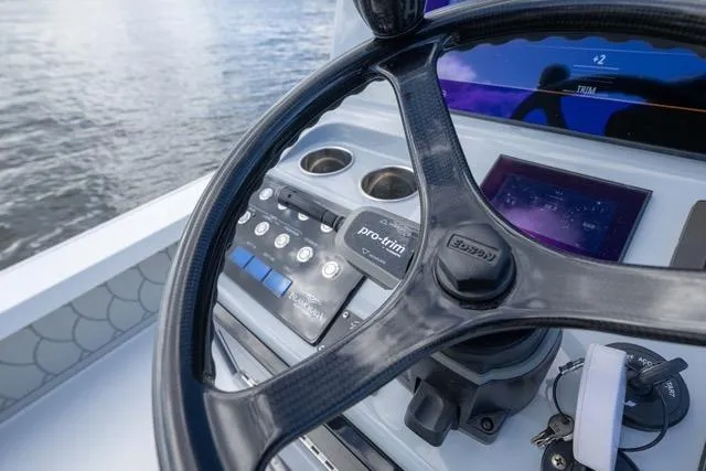  Yacht Photos Pics 2024 Islamorada Boatworks 24 helm with steering wheel, controls, and digital display on water.