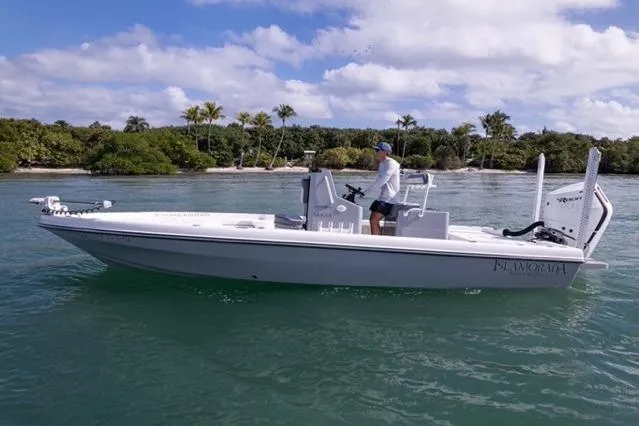  Yacht Photos Pics 2024 Islamorada Boatworks 24 cruising on clear water near a tropical shoreline.