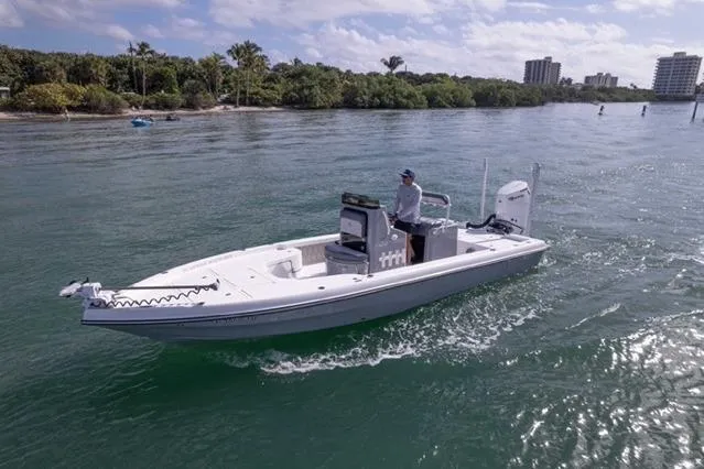  Yacht Photos Pics 2024 Islamorada Boatworks 24 cruising on a scenic waterway with lush greenery and buildings.