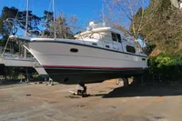 1996 Nimbus Trawler 37 boat on dry dock, surrounded by trees and clear blue sky.