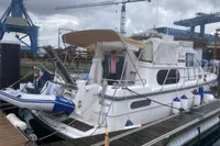 Nimbus Trawler 37, 1996 model, docked with inflatable boat, industrial background.