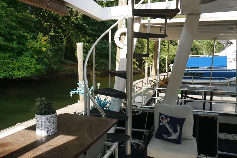  Yacht Photos Pics Houseboat interior with spiral staircase, anchor-themed decor, and lush riverside view. STARDUST Cruiser 1996.