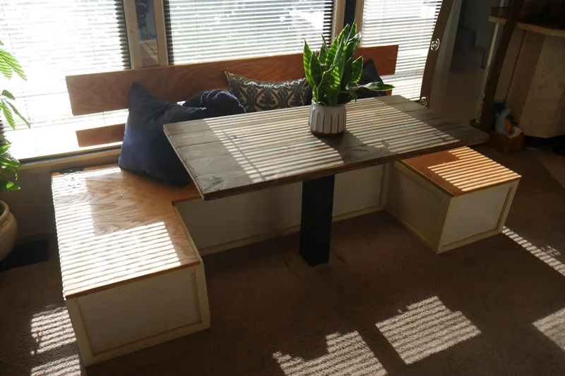  Yacht Photos Pics Cozy dining nook with wooden table, bench seating, and decorative pillows in a STARDUST Cruiser, 1996.