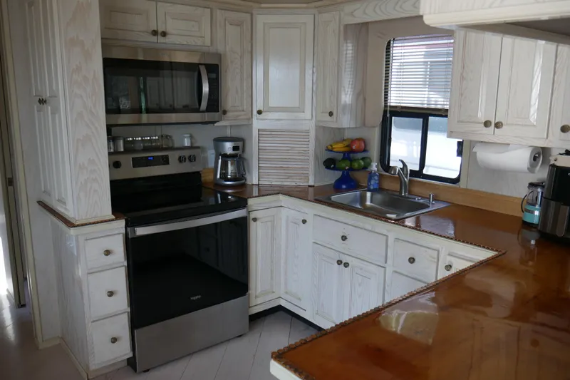  Yacht Photos Pics 1996 STARDUST Cruiser kitchen with white cabinets, stainless steel appliances, and wooden countertops.