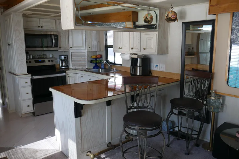  Yacht Photos Pics Modern kitchen interior in a 1996 STARDUST Cruiser, featuring white cabinetry and stainless steel appliances.