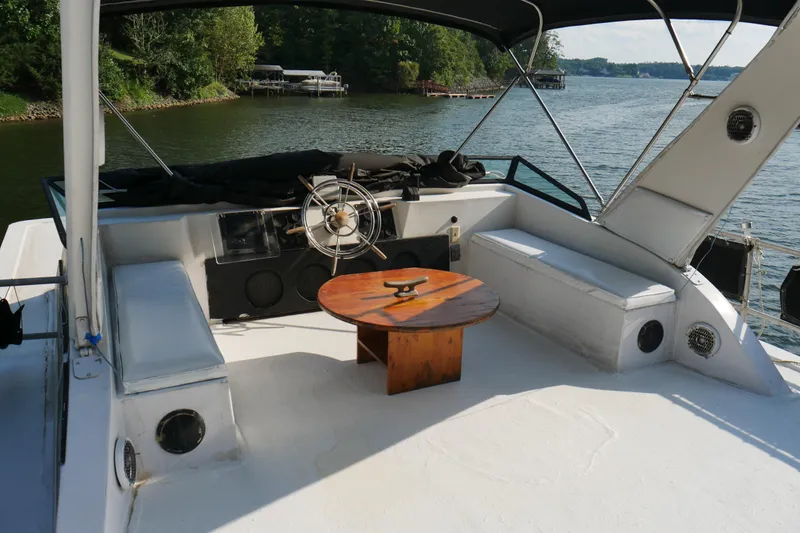  Yacht Photos Pics 1996 STARDUST Cruiser boat deck with seating, steering wheel, and wooden table on a serene lake.