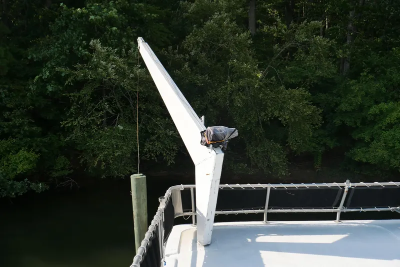  Yacht Photos Pics Rooftop view of 1996 STARDUST Cruiser boat with crane arm and lush forest background.