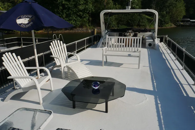  Yacht Photos Pics 1996 STARDUST Cruiser boat deck with chairs, table, and umbrella on a sunny day.