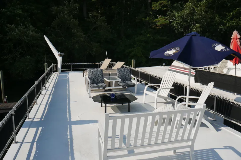  Yacht Photos Pics Rooftop deck of 1996 STARDUST Cruiser with seating and umbrellas, surrounded by lush greenery.