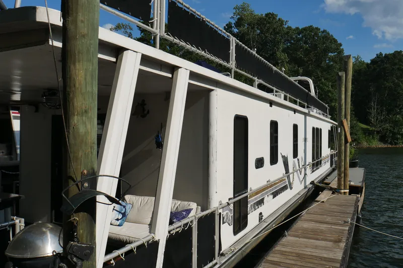  Yacht Photos Pics 1996 STARDUST Cruiser houseboat docked on a sunny day, surrounded by lush greenery.