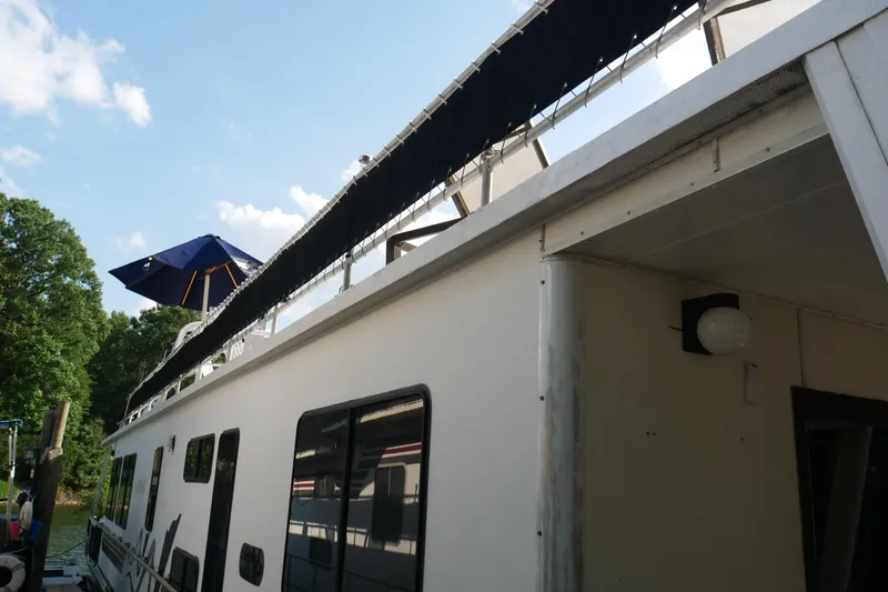  Yacht Photos Pics 1996 STARDUST Cruiser boat with blue canopy, docked near lush greenery.