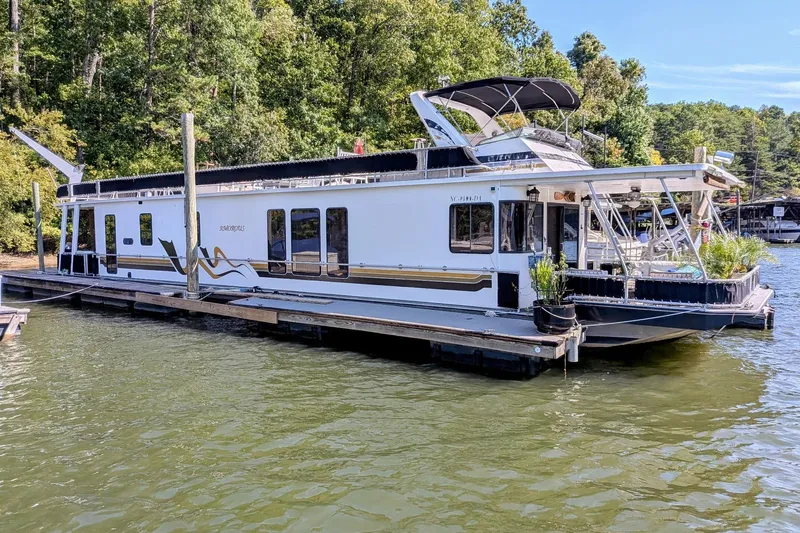  Yacht Photos Pics 1996 Stardust Cruisers houseboat docked on a serene lake with lush greenery.