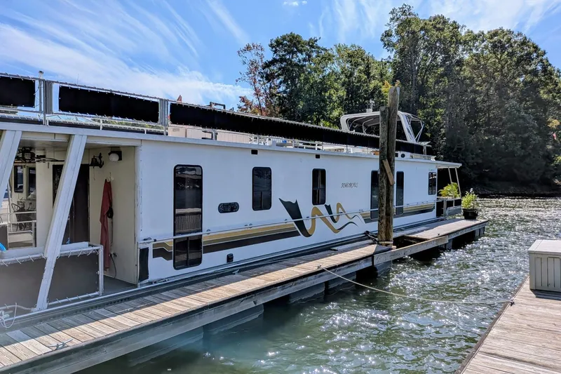  Yacht Photos Pics 1996 Stardust Cruisers houseboat docked on a sunny day, surrounded by trees and water.