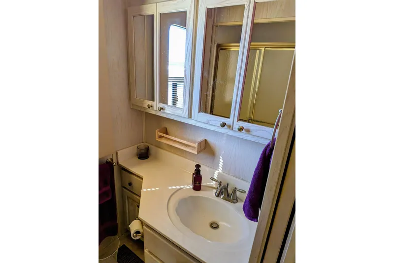  Yacht Photos Pics Bathroom vanity in 1996 Stardust Cruisers houseboat, featuring sink, mirror, and storage cabinets.