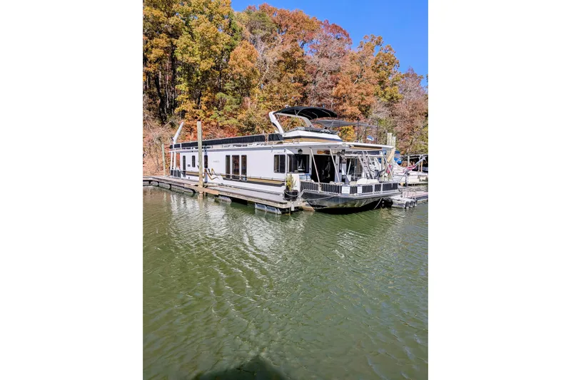  Yacht Photos Pics 1996 Stardust Cruisers houseboat docked on a lake with autumn trees in the background.