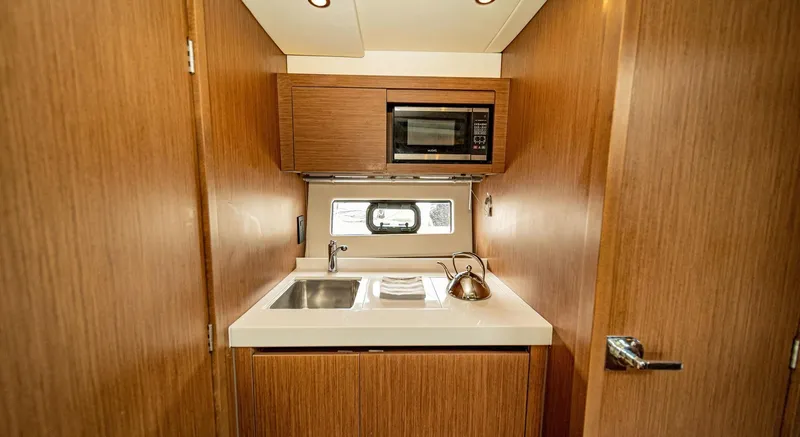 Yacht Photos Pics Compact kitchen area in 2024 Beneteau 36 Gran Turismo GT yacht with sink and microwave.