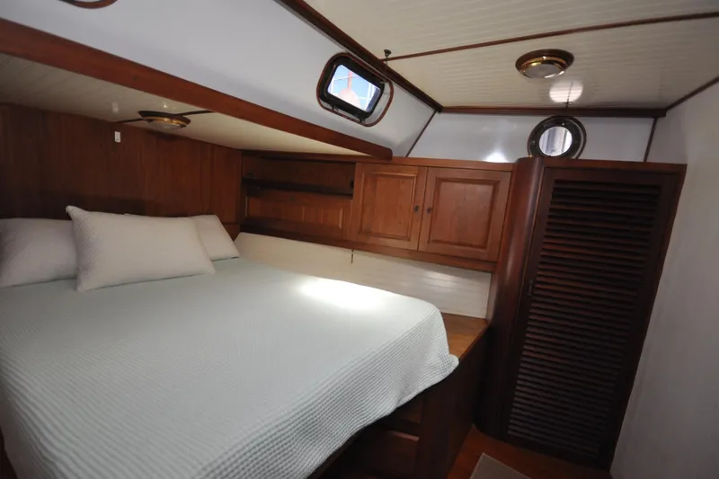 In The Flow Yacht Photos Pics Cozy cabin interior of 1982 Custom Virpack Steelhull with wooden furnishings and porthole windows.
