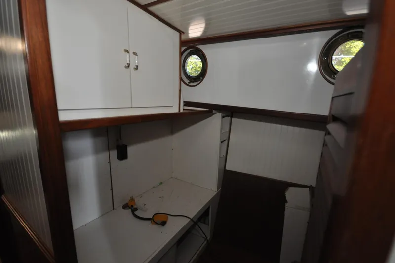 In The Flow Yacht Photos Pics Interior of 1982 Custom Virpack Steelhull boat with white cabinets and porthole windows.
