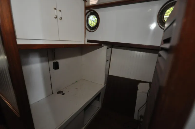 In The Flow Yacht Photos Pics Interior of 1982 Custom Virpack Steelhull boat with white cabinets and porthole windows.