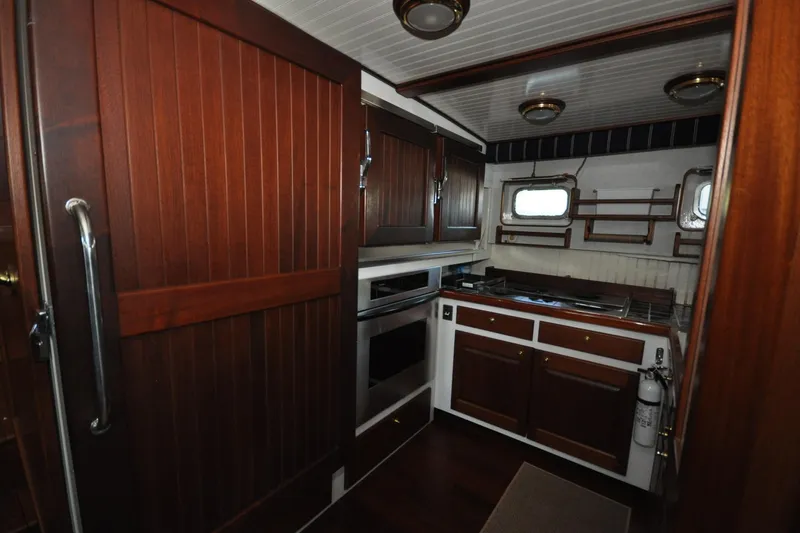 In The Flow Yacht Photos Pics Interior of 1982 Custom Virpack Steelhull yacht kitchen with wooden cabinets and modern appliances.