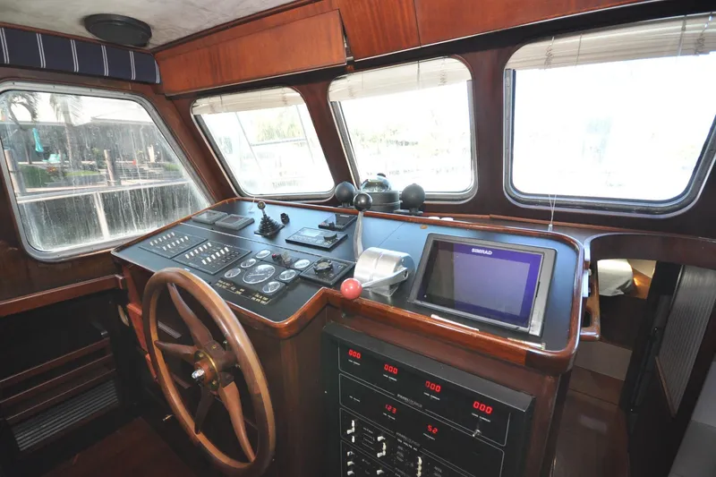 In The Flow Yacht Photos Pics Interior helm of 1982 Custom Virpack Steelhull boat with navigation controls and wooden steering wheel.