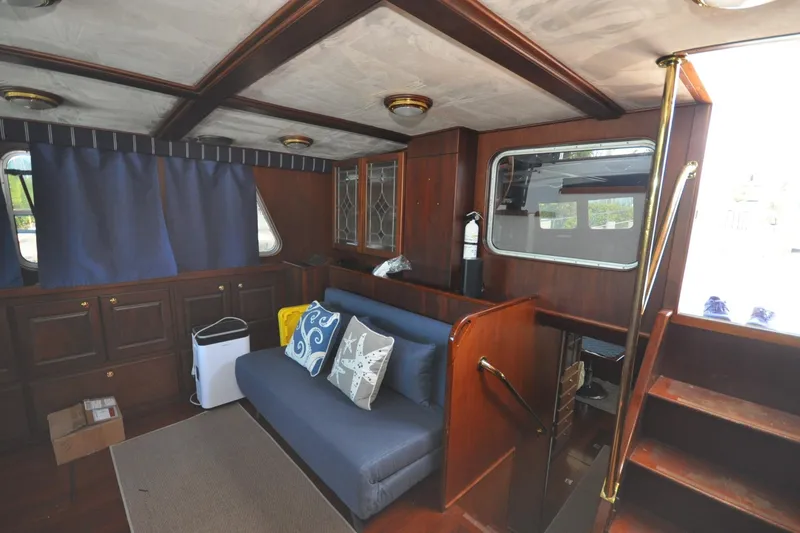 In The Flow Yacht Photos Pics Interior of 1982 Custom Virpack Steelhull boat with wooden furnishings and blue sofa.