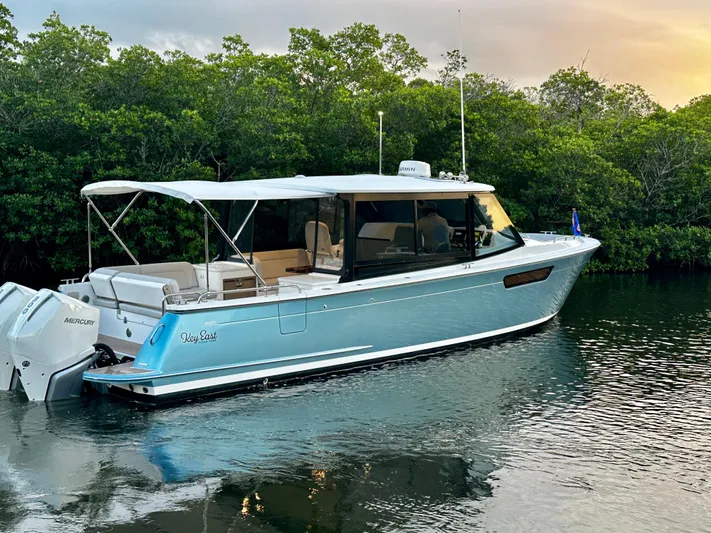 Key East Yacht Photos Pics 2023 MJM 3 boat on calm water, surrounded by lush greenery.