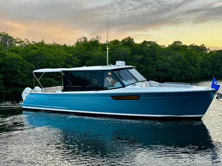 Key East Yacht Photos Pics 2023 MJM 3 boat on calm water at sunset, surrounded by lush greenery.