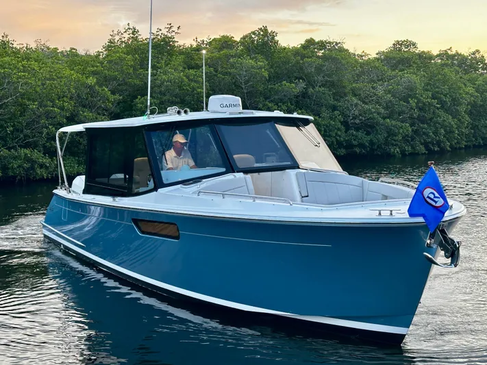 Key East Yacht Photos Pics 2023 MJM 3 boat cruising on a calm river with lush greenery.