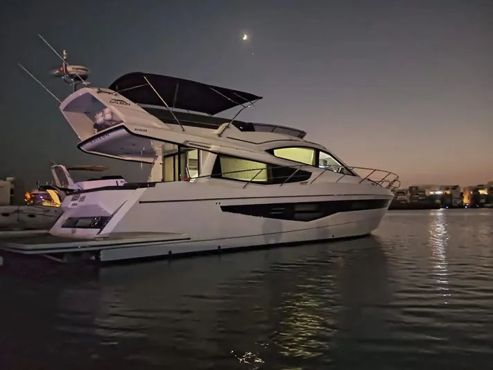 Sadeen Yacht Photos Pics Galeon 550 Fly 2016 yacht at dusk on calm water, under a crescent moon.