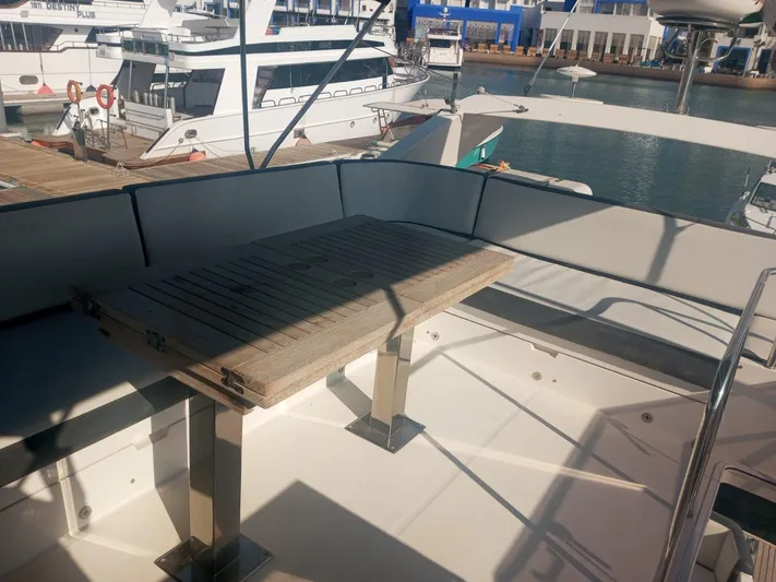 Sadeen Yacht Photos Pics 2016 Galeon 550 Fly yacht deck with wooden table and seating area.