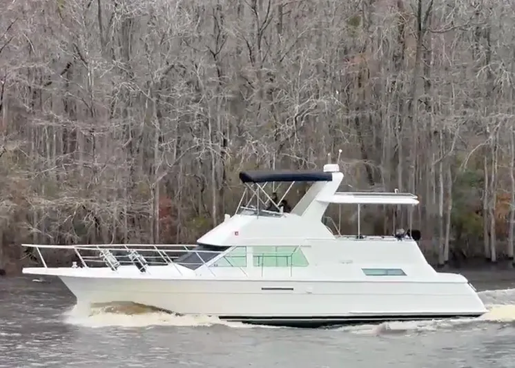 New Moon Yacht Photos Pics 1996 Hatteras 42 CPMY yacht cruising on a river with forested background.