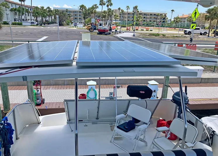 New Moon Yacht Photos Pics 1996 Hatteras 42 CPMY yacht with solar panels and seating area, docked near palm trees.